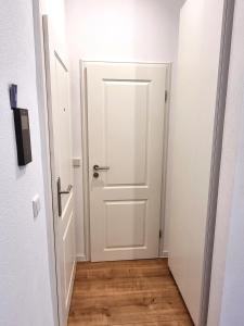 a white door in a hallway with a wooden floor at Modernes Apartment im Zentrum von Karlsruhe in Karlsruhe