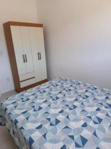 een slaapkamer met een bed met een blauw en wit patroon bij Apartamento em Itapema- 10k de Balneário Camboriú in Itapema