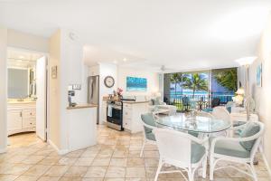 a kitchen and dining room with a glass table and chairs at ***SERENDIPITY ON THE MOANA - Legal & Oceanfront - Great for Work & Play!*** in Waianae