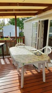 une table et des chaises blanches sur une terrasse en bois dans l'établissement Bungalow de 3 chambres avec piscine partagee jardin amenage et wifi a Onzain, à Onzain