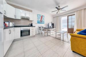 uma cozinha e sala de estar com uma mesa e um sofá em Casa Appia-300m from the beach, heated pool em Puerto del Carmen