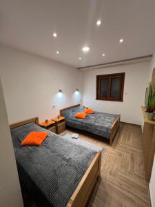 2 Betten in einem Zimmer mit orangefarbenen Kissen in der Unterkunft Apartmani Ristanović Užice in Užice