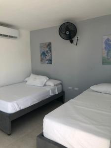 2 camas en una habitación con paredes blancas en Manglearena en Tolú