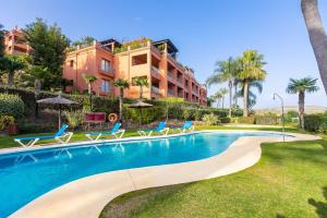 a swimming pool with chairs and a building at Royal Flamingos Sea View Apartman in Estepona