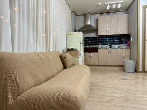 a living room with a couch and a kitchen at Sacheon Songlim in Gangneung