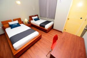um quarto com 2 camas, uma secretária e uma cadeira em HOSTAL LANCELOT em Chiclayo