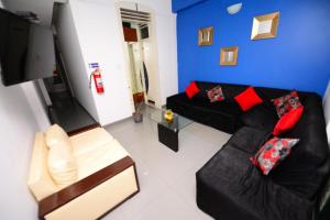 sala de estar con sofá negro y almohadas rojas en HOSTAL LANCELOT, en Chiclayo