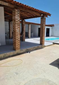 a brick pavilion with a pool in the background at Casa com piscina Forte Orange- Itamaracá in Itamaracá