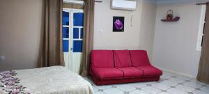 Silla rosa en una habitación con cama en Bel appartement, en El Kala
