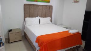 a bedroom with a large bed with an orange blanket at Karin Hotel in Ríohacha