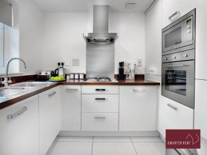 a white kitchen with a sink and a stove at Bracknell - 2 Bedroom House With Garden in Bracknell +4 photos