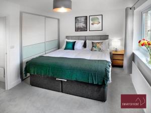 a bedroom with a large bed with a green blanket at Bracknell - 2 Bedroom House With Garden in Bracknell