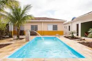 a swimming pool in front of a house at Piscina 6 QUARTOS 300mPRAIA jardim churrasqueira 16 PESSOAS garagem 3 carros Monitoramento 24 horas Mesa de sinuca in Itanhaém