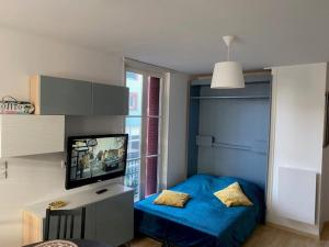 een slaapkamer met een blauw bed en een televisie bij NOUVEAU: Charmant appartement de 35m² in Mers-les-Bains