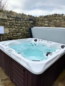 a large bath tub sitting next to a stone wall at Converted Barn with Hot Tub, The Hayloft. in Over Kellet