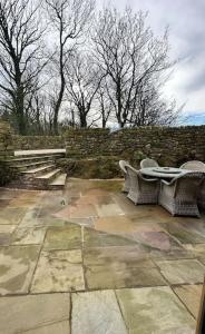 a patio with two tables and chairs and a stone wall at Converted Barn with Hot Tub, The Hayloft. in Over Kellet