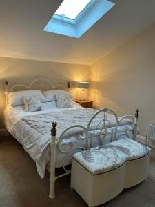 a bedroom with a white bed with a skylight at Converted Barn with Hot Tub, The Hayloft. in Over Kellet