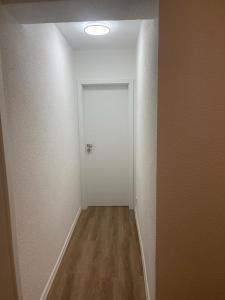 an empty hallway with a white door and wooden floors at Hotel Weibertreu in Weinsberg