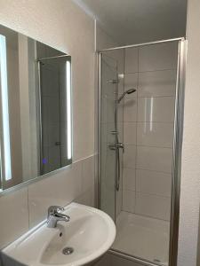 a bathroom with a sink and a shower with a mirror at Hotel Weibertreu in Weinsberg