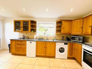 cocina con armarios de madera, lavadora y secadora en Tillicoultry Jupiter Apartment - Scotland Holiday Let en Tillicoultry