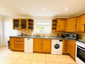 a kitchen with wooden cabinets and a washer and dryer at Tillicoultry Jupiter Apartment - Scotland Holiday Let in Tillicoultry