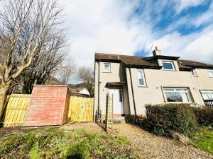 una casa blanca con una puerta y una valla en Tillicoultry Jupiter Apartment - Scotland Holiday Let en Tillicoultry