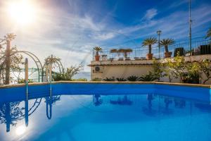 a swimming pool with blue water in front of a building at Villa Capriccio Sorrento Coast - Capri view villa by the sea in Massa Lubrense