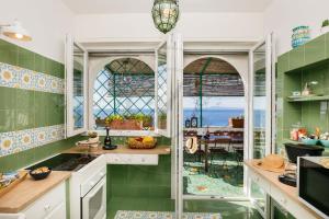 a kitchen with green tiles and a view of the ocean at Villa Capriccio Sorrento Coast - Capri view villa by the sea in Massa Lubrense