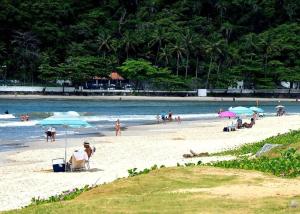 un grupo de personas en una playa con sombrillas en Piscina 6 QUARTOS 300mPRAIA jardim churrasqueira 16 PESSOAS garagem 3 carros Monitoramento 24 horas Mesa de sinuca, en Itanhaém