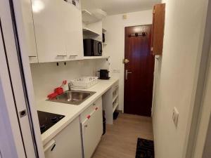 a small kitchen with white cabinets and a sink at Studio Courchevel, 1 pièce, 2 personnes - FR-1-514-80 in Courchevel