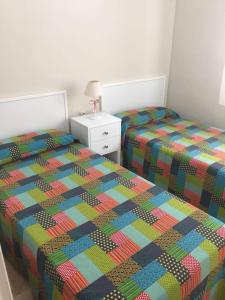two twin beds in a bedroom with a colorful comforter at Gran piso familiar in Córdoba