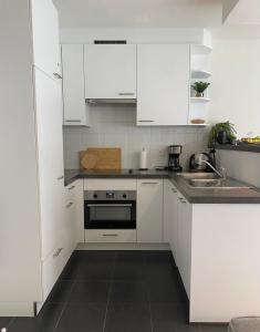 een witte keuken met witte kasten en een wastafel bij Petit plage Nieuwpoort-Bad in Nieuwpoort