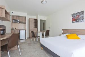 1 Schlafzimmer mit einem weißen Bett und einer Küche in der Unterkunft Kosy Appart'hôtels Art'&Facts in Nancy