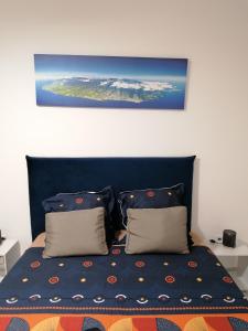 łóżko z niebieskim zagłówkiem i 2 poduszkami w obiekcie Kaela spa balneo w mieście Le Port