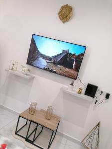 telewizor z płaskim ekranem wiszący na ścianie ze stołem w obiekcie Kaela spa balneo w mieście Le Port