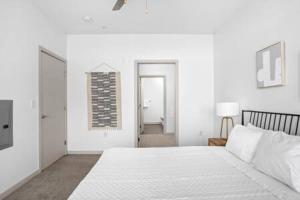 a white bedroom with a large bed and a hallway at CozySuites 2BD Bottleworks Indianapolis #2 in Indianapolis