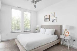 a white bedroom with a large bed and a window at CozySuites l Trendy 2BR, Bottleworks Indy #1 in Indianapolis