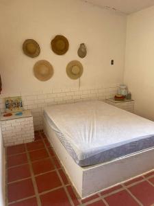 Casa de praia em Muriú في Ceará-Mirim: غرفة نوم مع سرير وبعض القبعات على الحائط