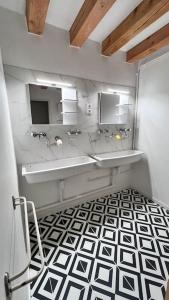 ein Bad mit 2 Waschbecken und einem schwarz-weißen Boden in der Unterkunft Appartement au pied des Vignes in Vosne-Romanée