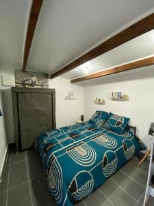 Schlafzimmer mit einem Bett mit einer blauen und weißen Bettdecke in der Unterkunft studio 20 min aéroport CDG in Othis