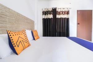 Sohāna的住宿－OYO Spring Woods Suites，卧室配有带橙色枕头的大型白色床