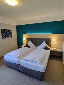 1 dormitorio con 1 cama grande con sábanas blancas en BurgStadt-Hotel, en Kastellaun