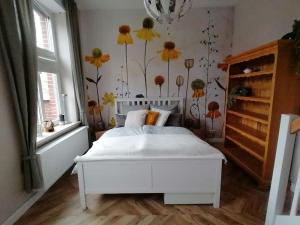a bedroom with a white bed with flowers on the wall at Gemütliche Ferienwohnung in Neu Kaliß in Neu Kaliß