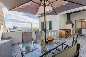 a table with food and an umbrella on a patio at SUNSET VILLA in Caniço