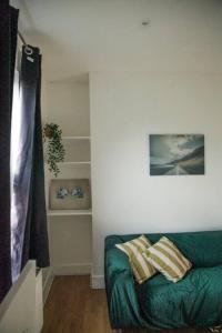 a living room with a green couch with pillows on it at 2 New bed flat in hammersmith in London