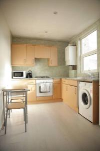 a kitchen with a table and a washing machine at 2 New bed flat in hammersmith in London