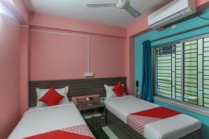 two beds in a room with pink and blue walls at Hotel O Prime International in New Town