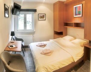 1 dormitorio con cama, escritorio y ventana en Hotel Auberge Rustique, en Beaufort