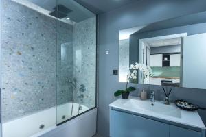 a blue bathroom with a tub and a sink at Korai Suites by Good Life in Heraklio Town