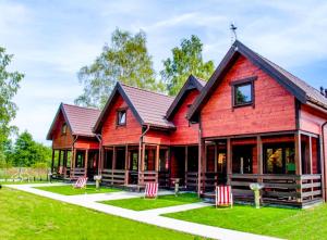 ein rotes Haus mit roten Stühlen davor in der Unterkunft Ośrodek Wypoczynkowy IDA in Mielenko